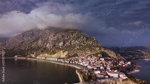 Cozy hillside village nestled against mountain with terraced houses and narrow lanes cascading toward bay in warm lateafternoon light. Intimate local charm ideal for lifestyle and destination stories