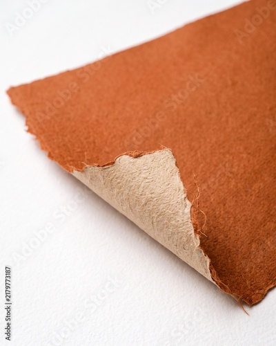Close-up View of Terracotta Colored Handmade Paper Sheet with Rough Deckle Edges and Visible Texture