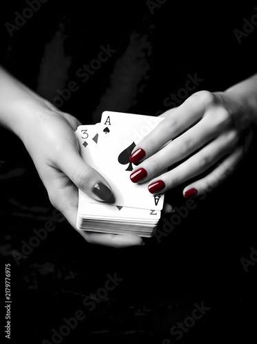 Playing Cards Held by Woman with Dark Red Manicure Against a Solid Black Background