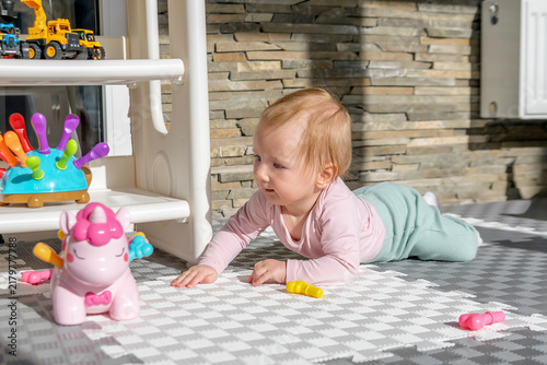 Cute little baby lying on stomach,girl playing at home with toys sucking,exploring teething textured toys in playing room.Children logic development,early sensory education,happy childhood
