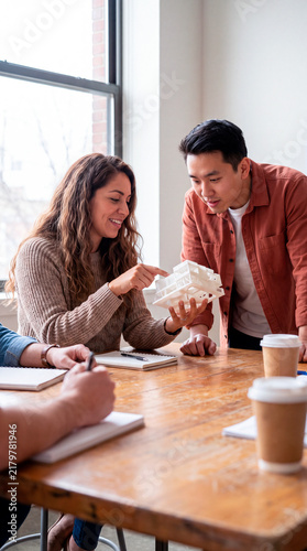 Colleagues examine white 3D printed architecture model during office meeting