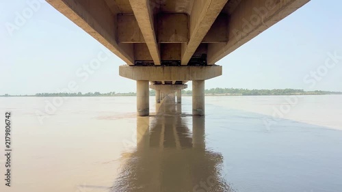 view of a wide river flowing peacefully beneath a sturdy bridge in a scenic rural landscape. 4k video