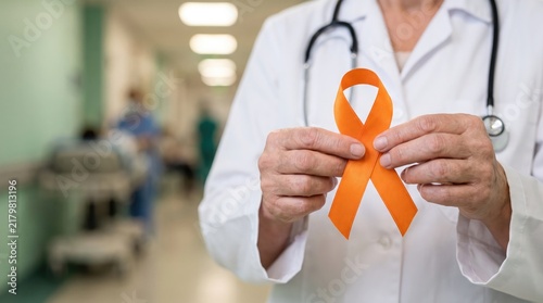Doctor holding an orange ribbon representing leukemia awareness in a hospital corridor