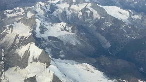 Flying over the European Alps during summer season. Landscape at the glaciers. Melting of glaciers due to global warming. Aerial view from the airplane window