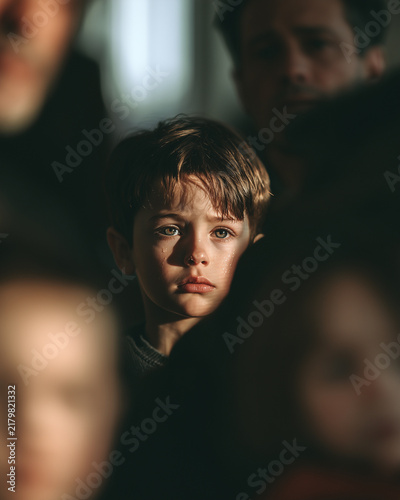 Vulnerable Child Sitting Between Blurred Parents During Family Conflict