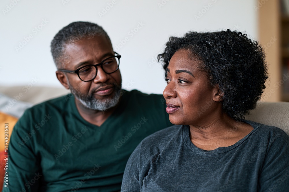 Obraz premium Mature couple sharing supportive conversation on modern sofa at home