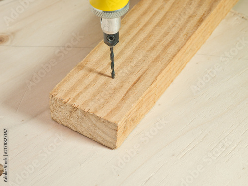 Foto Drill Bit Penetrating Wooden Plank - A close-up view of a metal drill bit from a