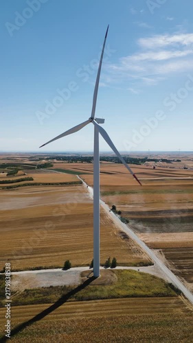 Renewable energy and sustainability, wind turbine generating electricity in a rural field, vertical aerial drone shot of clean power infrastructure