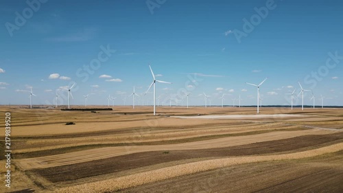 Aerial drone footage of a wind farm, tracking motion to the right over rural agricultural fields, green energy generation in the countryside