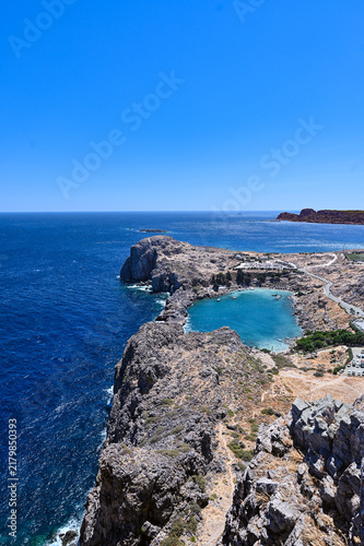 Aerial view of rocky coastline and turquoise bay under clear blue sky - Saint Paul's Bay at Lindos, Rhodes Island, Greece