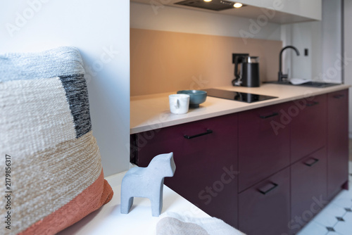 Interior of a hotel room with small kitchen with purple furniture and pillow as a decor. Studio apartment with decoartion.