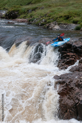 Kayaker navigating a challenging river drop, engaging in adventurous water extreme sports