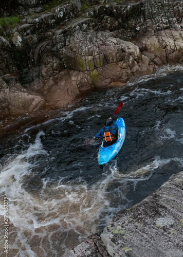 Kayaker descending waterfall drop on rough river. Extreme sports