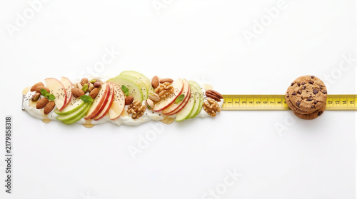 Measuring tape linking a row of fresh apple slices, nuts, seeds, and yogurt to stacked chocolate cookies, conceptual 3D render representing dietary choices, waist measurement, obesity prevention, and 