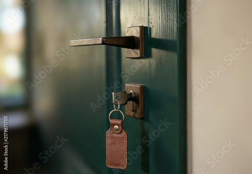 Obraz na płótnie Leather tag keyring hanging from key in door lock, ai generated. Close-up of blank brown tag, customizable leather keychain with metal ring and copy space for personalized engraving, branding.
