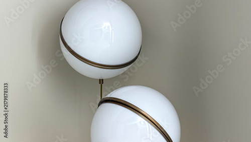 Modern spherical pendant lights with bronze details against a minimalist neutral wall in a contemporary interior.