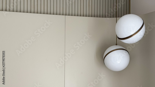 Modern spherical pendant lights with bronze details against a minimalist neutral wall in a contemporary interior.