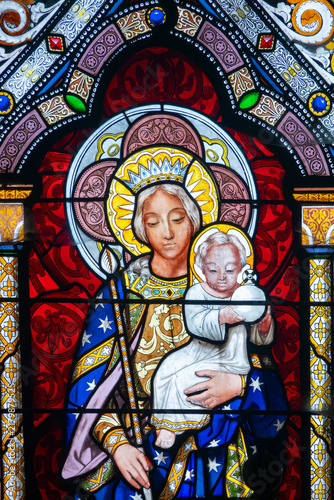 фотографія A stained glass window depicts the Virgin Mary holding the infant Jesus Christ with halos