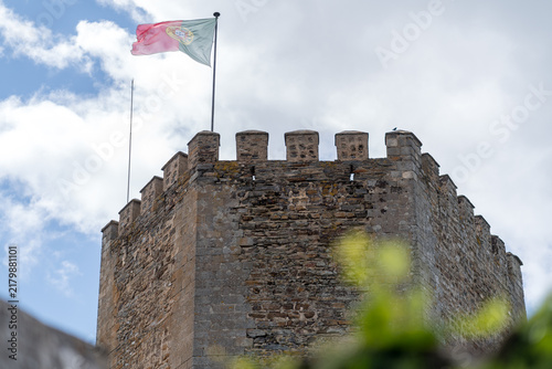 Monsaraz Castle Tower with Portuguese Flag Flying Against Cloudy Sky