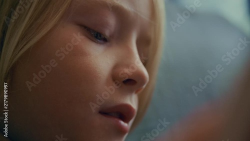 Profile view of a child concentrating while reading a storybook and quietly following the text. The intimate footage represents education, literature, knowledge, and youthful curiosity.