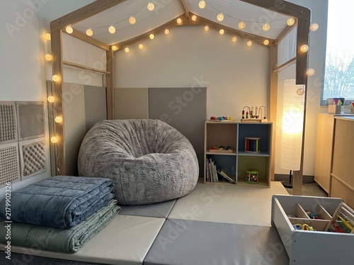 cozy sensory classroom corner with bean bag chair, house frame canopy, warm string lights, and calming learning toys