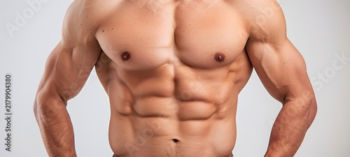 Muscular male torso displaying highly defined abdominal muscles and powerful pectorals captured in sharp detail with professional studio lighting techniques
