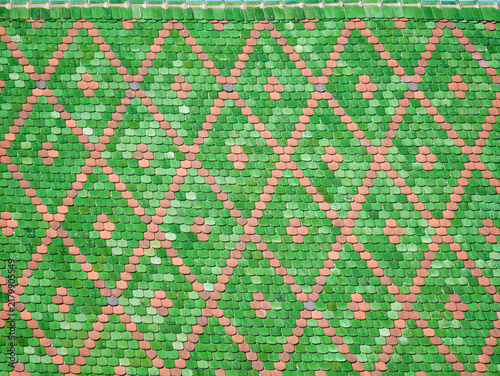 Close-up of a traditional colorful tiled roof in Alsace, France, featuring a decorative pattern of green and terracotta roof tiles.