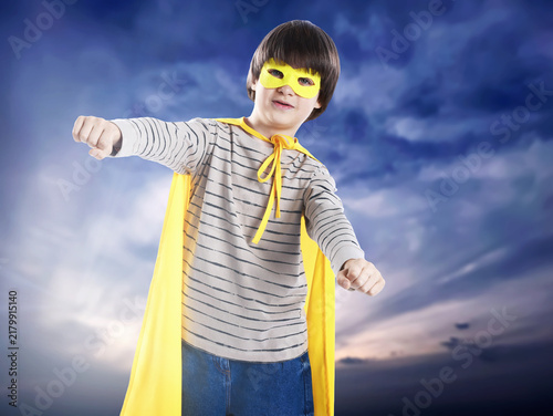 Obraz na plátně Little boy with yellow superhero cape and mask against sunset sky