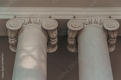 Konstfotografi A detailed close-up shot of the top capitals of two white neoclassical columns featuring decorative Ionic volutes and egg-and-dart ornamentation