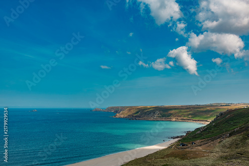 Photography Deep blue Atlantic water and a turquoise shallow shelf along the white beach of Whitesand Bay, Cornwall, with a rocky headland