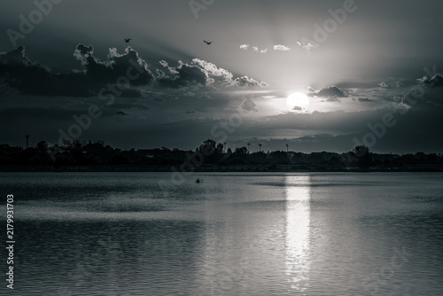 Black and white dramatic sky over Lacul Morii lake in Bucharest with kayakers.