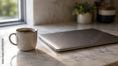 Coffee mug beside a closed laptop on a marble counter