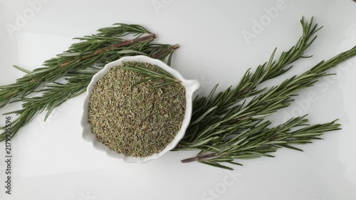 Fresh and dried rosemary spice slowly moving on a white plate