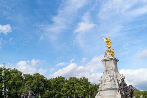 Canvas Print Golden Angel Statue On Stone Monument Under Blue Sky With White Clouds