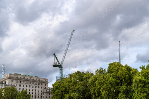 Photography Construction Crane Over Urban Trees and Building Under Cloudy Sky