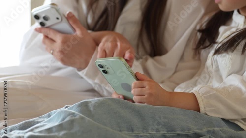リビングでスマートフォンを使う女の子とお母さん