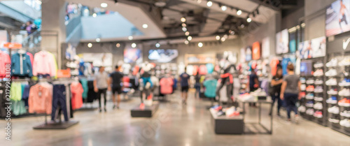 Modern sportswear retail store with fully blurred apparel racks, footwear displays, mannequins, and energetic lighting, creating a dynamic commercial background with clean copy space