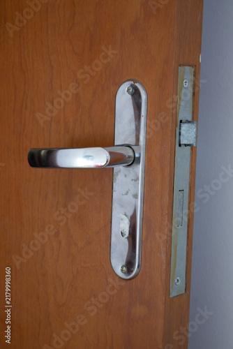 Close-up of a silver-colored metal door handle on a wooden door