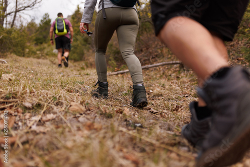 Fotografie Friends hiking on a mountain trail together with backpacks and boots on an autum