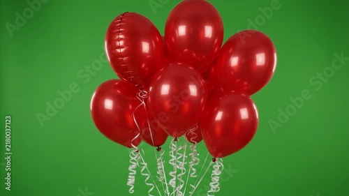 Bundle of shiny red balloons floating upwards against a green background on transparent background