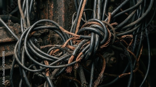 Tangled electrical cables and exposed copper wires in a dark industrial setting