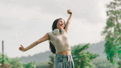 Fotografie Happy woman stretching in nature, raising arms outdoors, relaxing muscles while