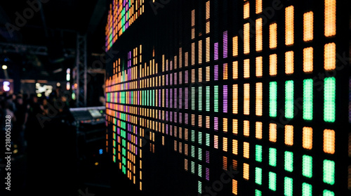 Colorful digital audio equalizer bars glowing on a dark background in a music studio