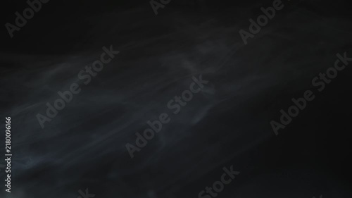 Atmospheric white smoke drifting slowly across dark black background in cinematic slow motion footage.