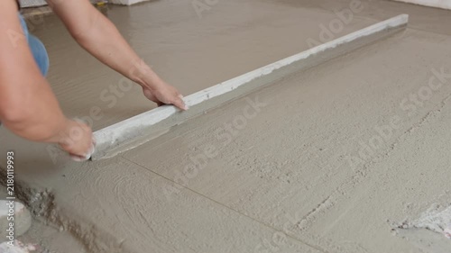 Construction Worker Leveling Fresh Concrete Floor Inside Residential House