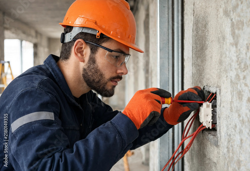 Electrician wears orange hard hat and gloves