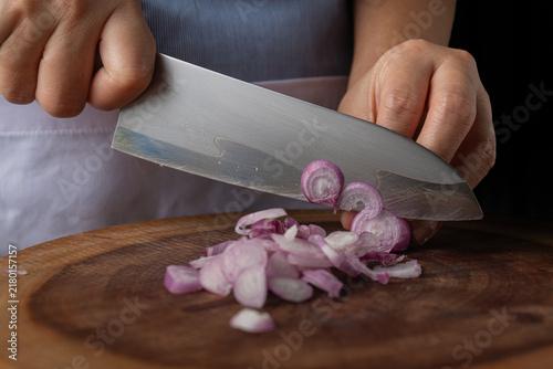 Bild auf Leinwand Close up of sharp chef knife blade slicing fresh purple shallots on wooden board