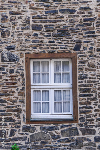 White Paned Window Framed by Rough Stone Masonry