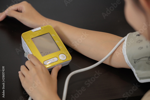 Cuadro en lienzo Woman checking blood pressure with digital monitor and arm cuff at home, representing healthcare, blood pressure monitoring, medical checkup, prevention, wellness, personal health care