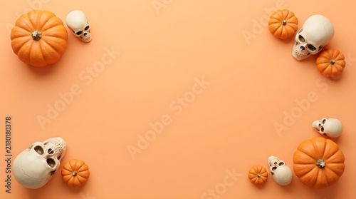 Halloween background with pumpkins and skulls arranged in corners on a vibrant orange flat lay surface